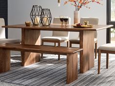 a dining room table with two benches next to it and a vase filled with flowers