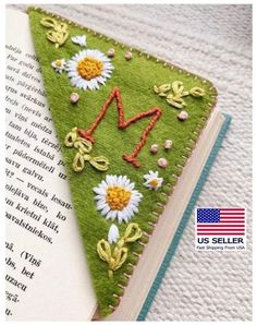 an open book with flowers on it and the words m is spelled in red, white, and blue