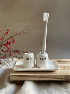 two toothbrushes sitting on a plate with the words his and hers written on them