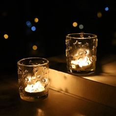 two lit candles sitting on top of a window sill