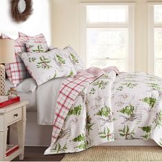 a bed with white and red comforters in front of a window next to a night stand