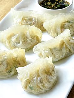 several dumplings on a white plate with dipping sauce