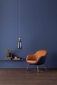 a living room with blue walls and an orange chair next to a plant on a table