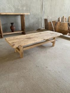 a wooden table sitting on top of a floor next to a shelf filled with vases