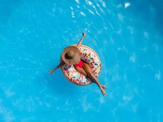 a woman floating on an inflatable donut with sprinkles wearing a hat