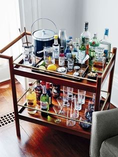 a bar cart filled with liquor bottles and glasses on top of a hard wood floor