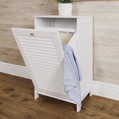 a white cabinet with a towel and potted plant in it next to a wooden wall