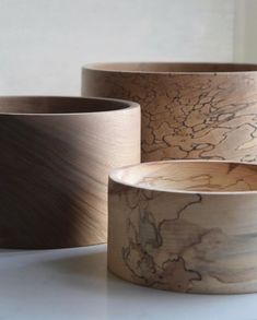 three wooden bowls sitting on top of a white counter