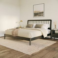 a large bed sitting on top of a wooden floor next to a night stand and nightstand