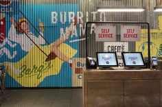 two laptops sitting on top of a wooden table in front of a store sign