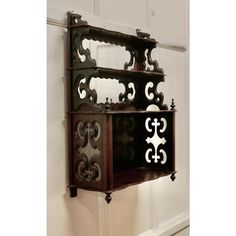 an old wooden shelf with ornate carvings on the front and back sides, mounted against a white wall