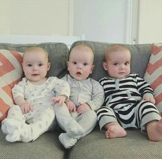 three babies are sitting on a couch together