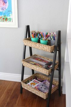 a three tiered shelf with books, pencils and markers in baskets on it