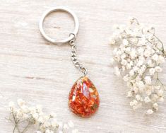 an orange tear shaped keychain sitting on top of a table next to flowers