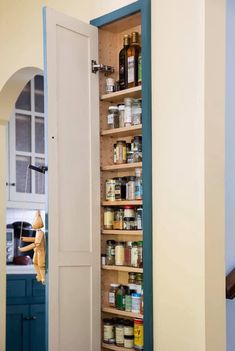 an open pantry door in a kitchen with spices and condiments on the shelves