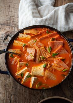 a pan filled with soup on top of a wooden table