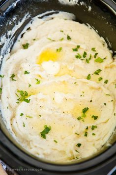 mashed potatoes in a crock pot with parsley on top, ready to be cooked