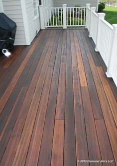 a wooden deck with white railings next to a house