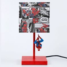 a lamp with spiderman pictures on it and a red stand that has two blue ribbons hanging from it