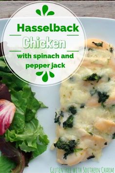 a white plate topped with spinach and cheese next to a salad on a wooden table