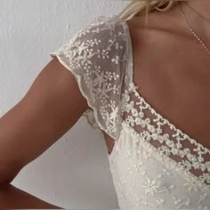 the back of a woman's wedding dress with white flowers on it and lace detailing