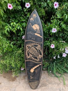 a surfboard sitting on the ground next to some flowers