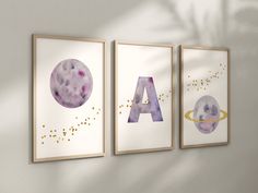 three art prints hanging on the wall with letters and planets in purple, yellow and blue