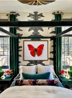 a bedroom with green curtains, white bedding and a red butterfly on the wall