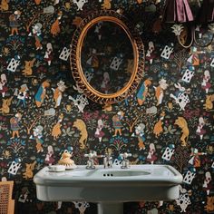 a bathroom sink sitting under a mirror next to a wall mounted faucet in front of a patterned wall