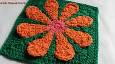 a crocheted square with an orange flower on it's center is shown