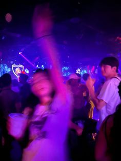 a group of people standing around in a room with purple lights on the walls and floor