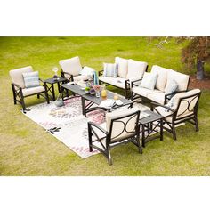 an outdoor patio furniture set with cushions and tables on the grass in front of some bushes