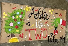 a sign that says addie is two and has a christmas tree painted on it