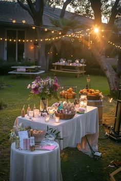 Outdoor evening gathering with decorated tables, fresh flowers, fruits, snacks, and candles under string lights, in a backyard garden setting. Party Setup Backyard, Cute Outdoor Birthday Party Ideas, Backyard Garden Dinner Party, Backyard House Party, 30th Birthday Backyard Party Ideas, Outside Party Aesthetic, Backyard 21st Birthday Party, Picture Wall Party, Engagement Party Outside