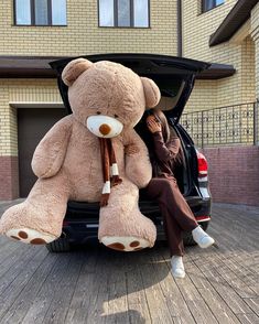 a person sitting in the back of a truck with a large teddy bear on it