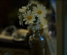 a vase filled with white daisies sitting on top of a table