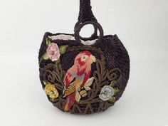 a small purse with an embroidered bird on the front and flowers on the outside, hanging from a hook