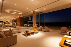 a living room filled with lots of furniture next to a large glass wall window at night