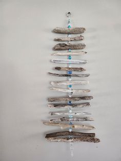 a christmas tree made out of driftwood and beads hanging from the side on a wall