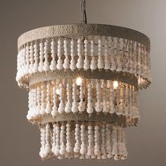 a chandelier hanging from the ceiling with beads and lights on it's sides