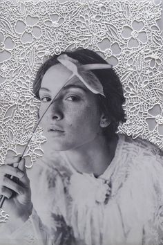 a black and white photo of a woman holding an umbrella over her head with lace on it