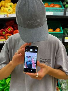 a person holding up a cell phone in front of a produce section