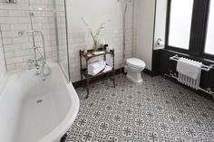 a white toilet sitting next to a bath tub in a bathroom with black and white tile