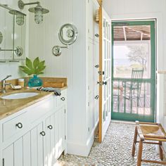 a bathroom with white walls and wooden floors, along with an open door leading to the outside