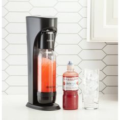 a black coffee maker sitting on top of a counter next to a bottle of liquid