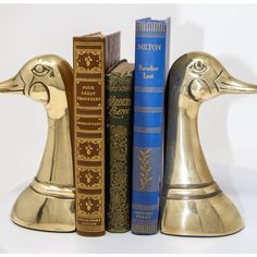 two golden duck bookends are next to each other in front of some books