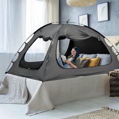 a woman sitting in a tent on top of a bed