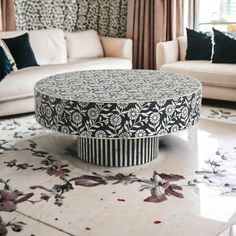 a living room with white couches and black and white patterned coffee table in the middle