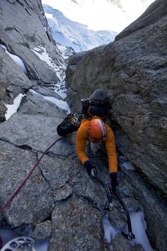 a man climbing up the side of a snow covered mountain