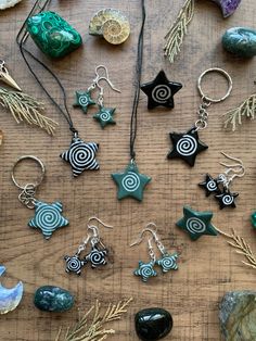 several different types of earrings and necklaces sitting on a table next to some rocks